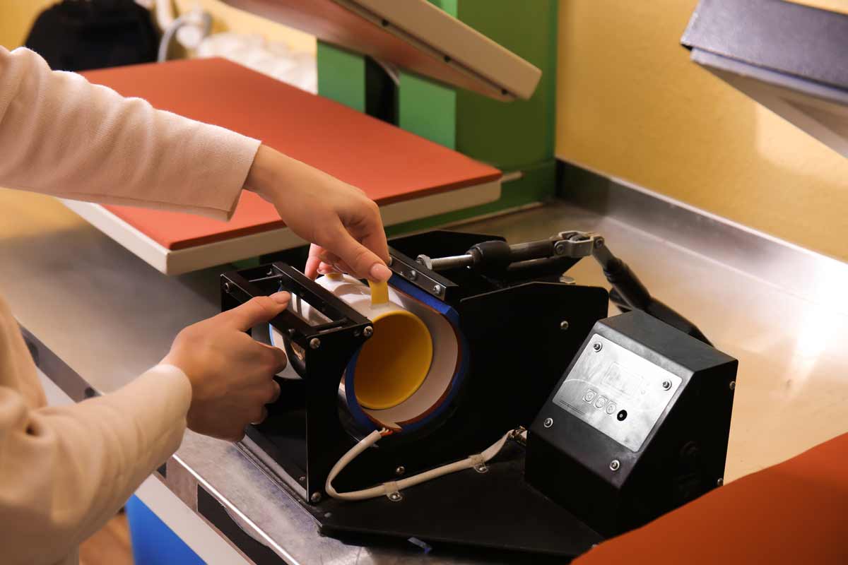 Dona serigrafiant una tassa al taller.